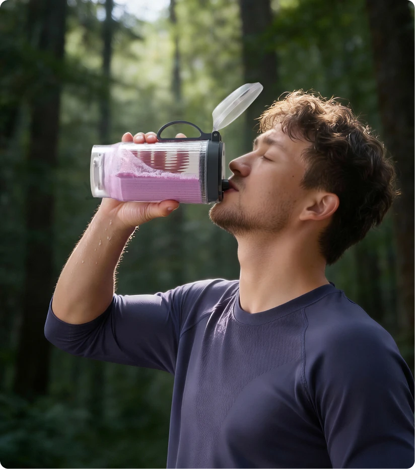 Gebruiker drinkt een smoothie uit de draagbare Dreame Portable Blender beker tijdens een boswandeling