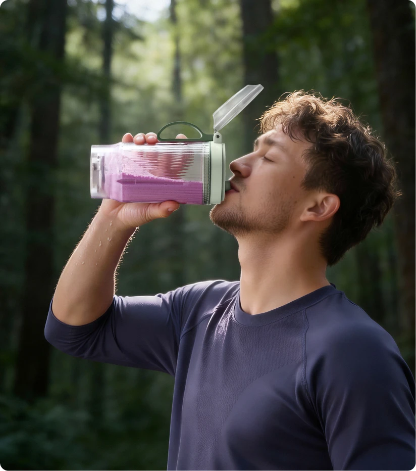 Gebruiker drinkt een smoothie uit de draagbare Dreame Portable Blender beker tijdens een boswandeling
