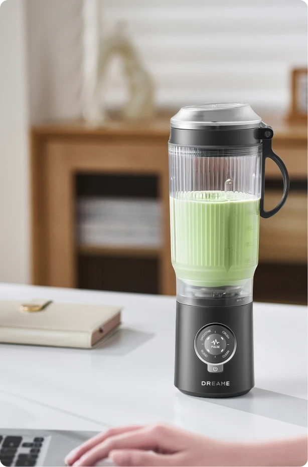 Dreame Portable Blender snoerloos ontwerp op een bureau mixt een groen drankje tijdens het werk