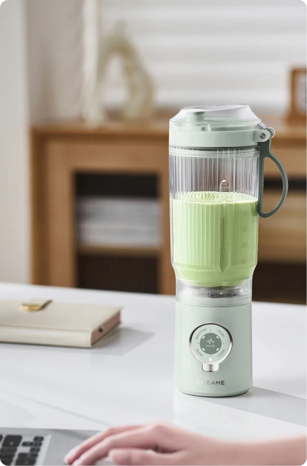 Dreame Portable Blender snoerloos ontwerp op een bureau mixt een groen drankje tijdens het werk