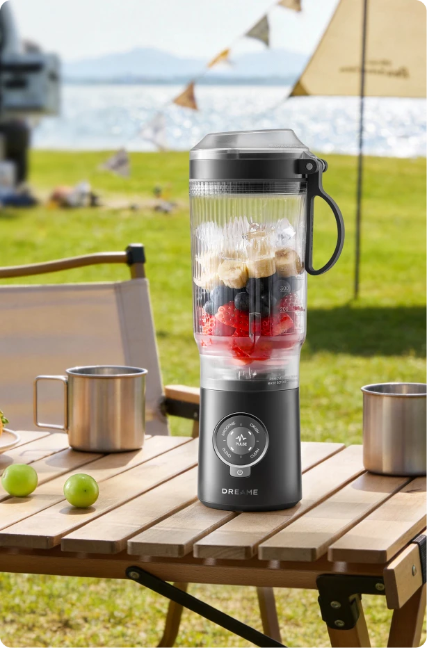Dreame Portable Blender snoerloos ontwerp op een picknicktafel mixt fruitdrankjes buiten aan het water
