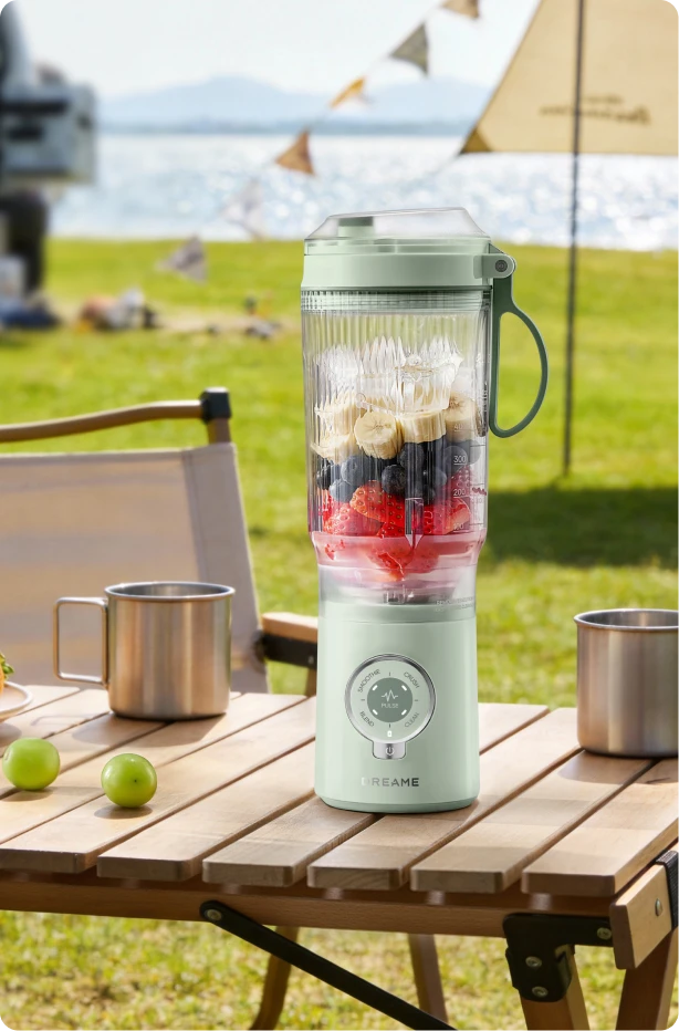 Dreame Portable Blender snoerloos ontwerp op een picknicktafel mixt fruitdrankjes buiten aan het water